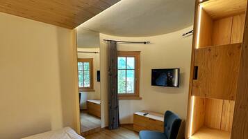 A bedroom with a bed, a chair, a TV, and a wooden shelf unit.
