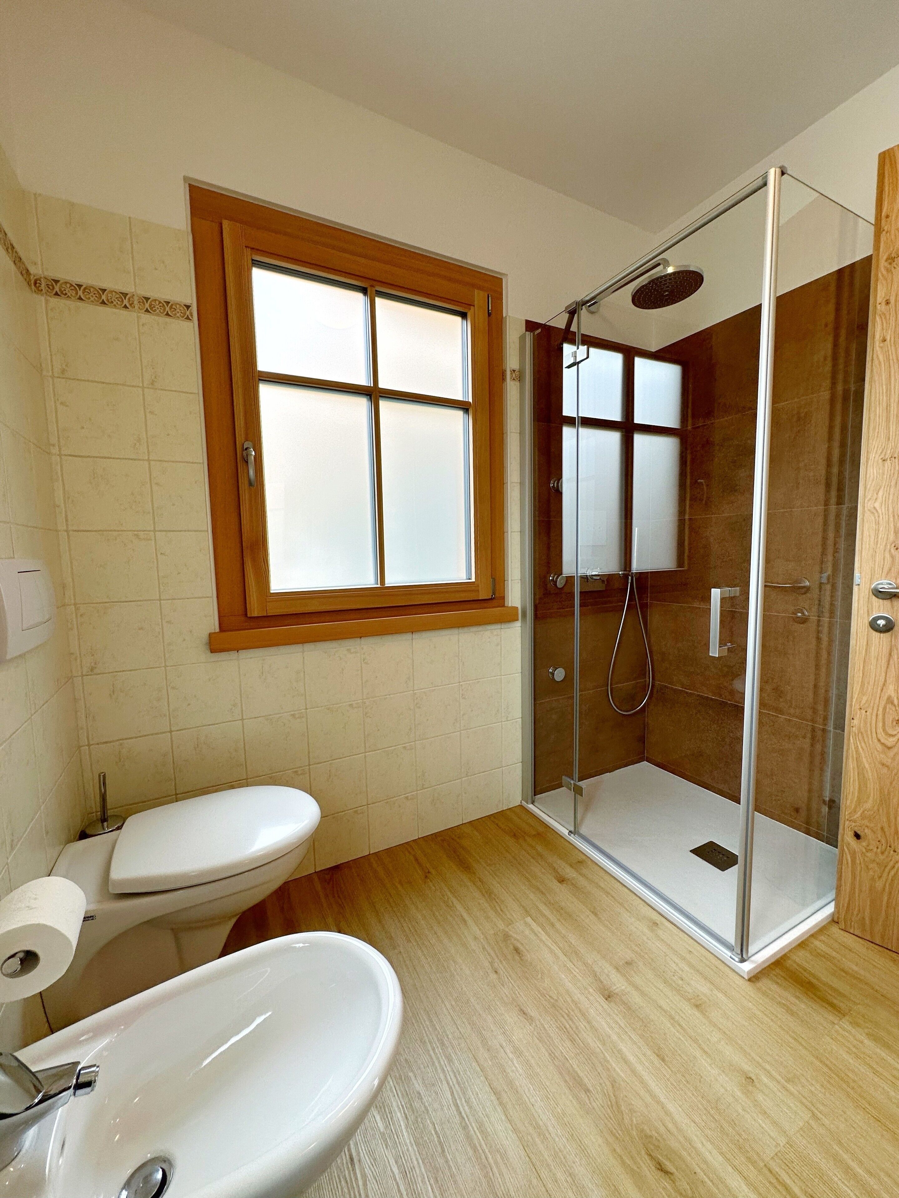 Un bagno con toilette, lavandino e cabina doccia in vetro.