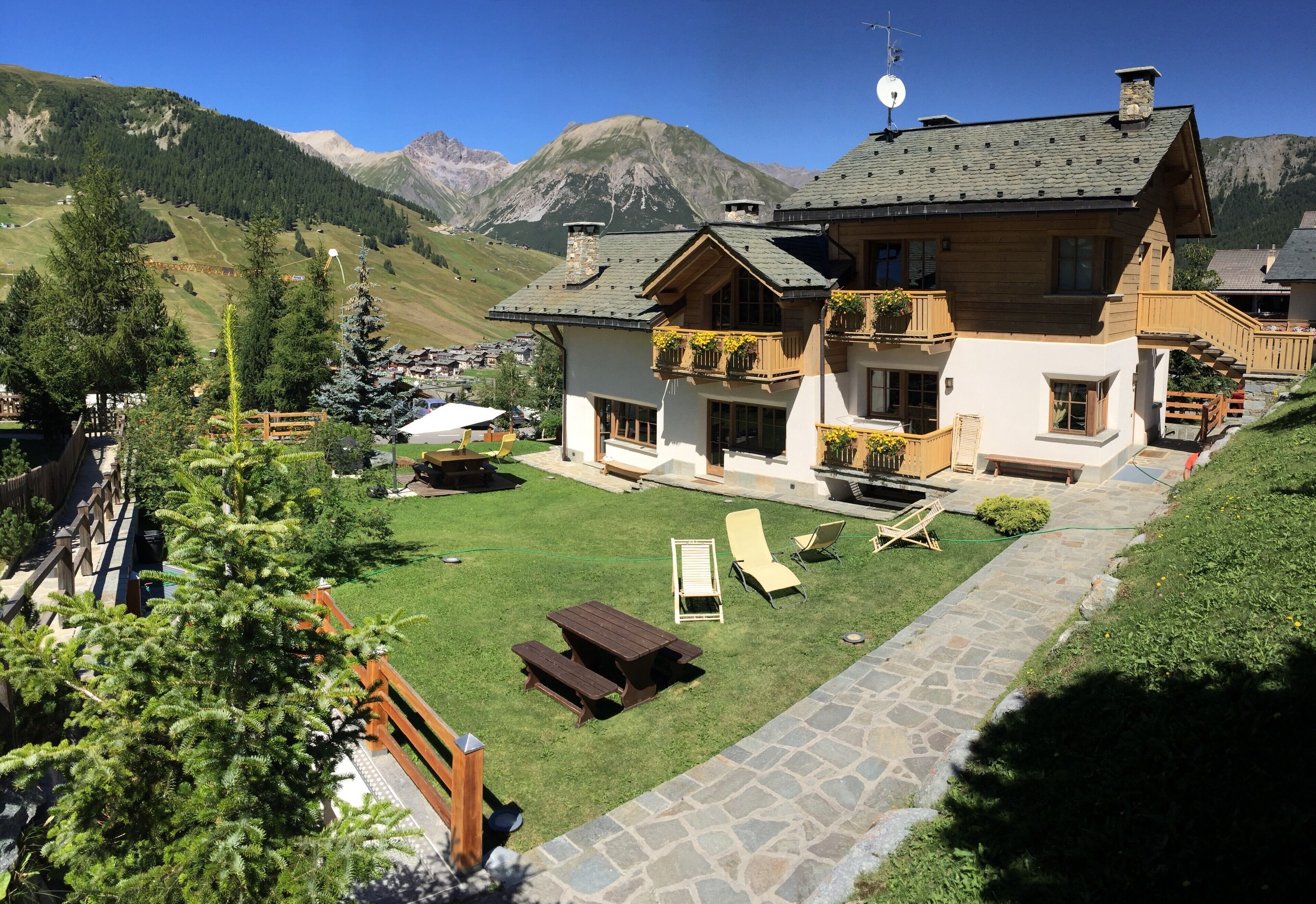 Un chalet doté d’un chemin en pierre, d’une terrasse en bois et offrant une vue sur les montagnes.