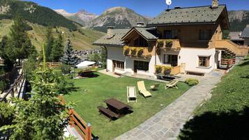 Un chalet doté d’un chemin en pierre, d’une terrasse en bois et offrant une vue sur les montagnes.