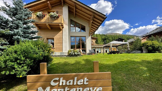 Un chalet con fachada de madera, un balcón con flores y un cartel que dice 'Chalet Monteneve'.