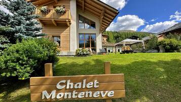 Un chalet avec une façade en bois, un balcon orné de fleurs et une enseigne indiquant « Chalet Monteneve ».