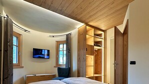 Un dormitorio con dos camas, televisión y techo de madera.