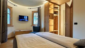 Une chambre avec deux lits, une télévision et un plafond en bois.
