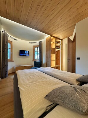 Une chambre avec deux lits, une télévision et un plafond en bois.