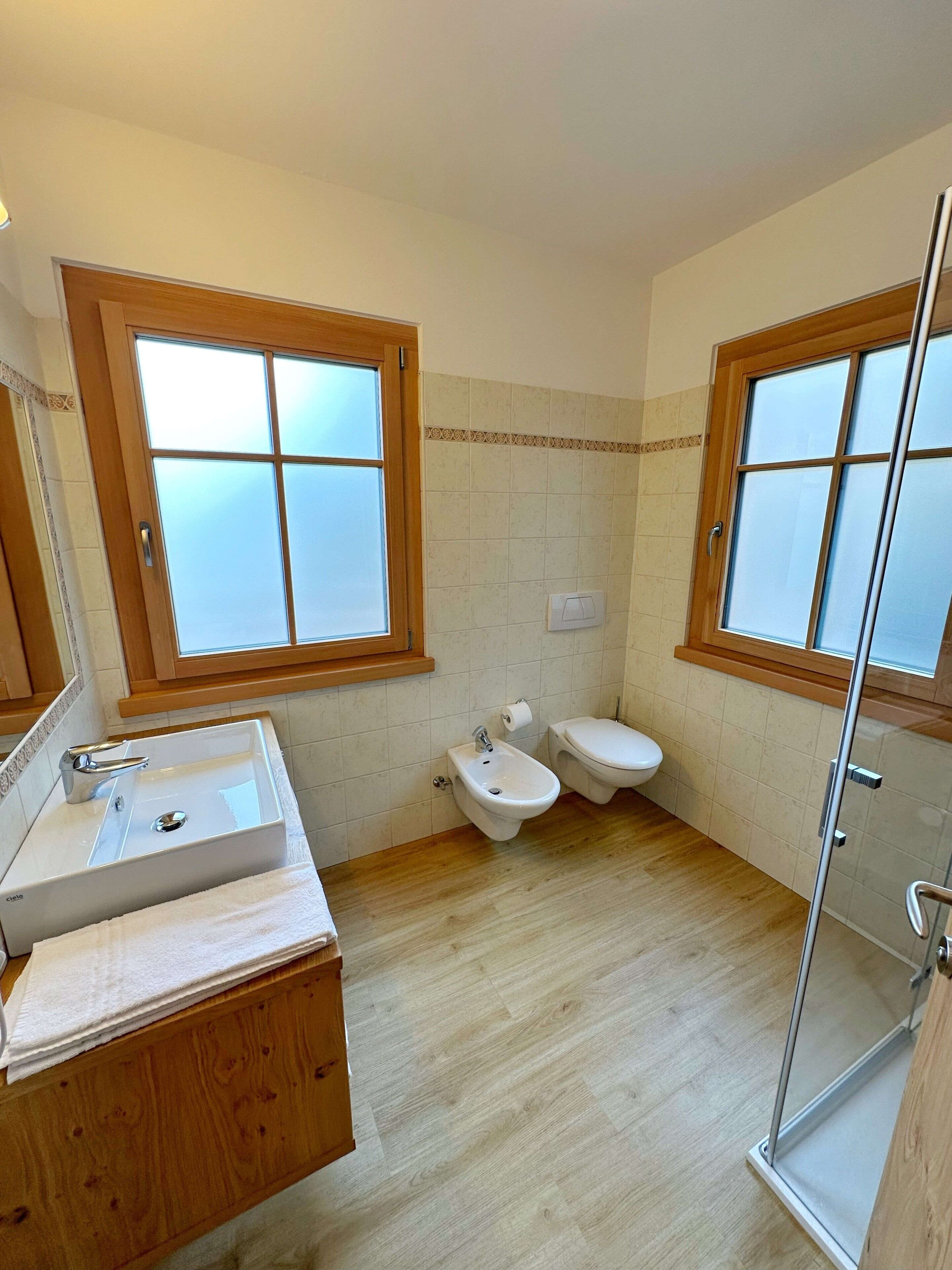 Et badeværelse med vask, bidet, toilet og brusekabine i glas.