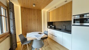 Una cocina moderna con armarios de madera, horno empotrado y una mesa de comedor con sillas.