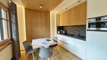 Une cuisine moderne avec des meubles en bois, un four encastré et une table à manger avec des chaises.