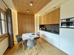 Una cucina moderna con mobili in legno, forno integrato e tavolo con sedie.