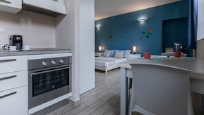 A modern kitchen with stainless steel appliances, a dining area with a table and chairs, and a living room with a sofa and decorative wall art. - Housing Giulia - Studio 2/4 by Wonderful Italy (Torino)