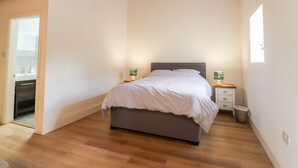 Une chambre à coucher avec un lit, des poutres en bois, une table de chevet, une lampe et une fenêtre.