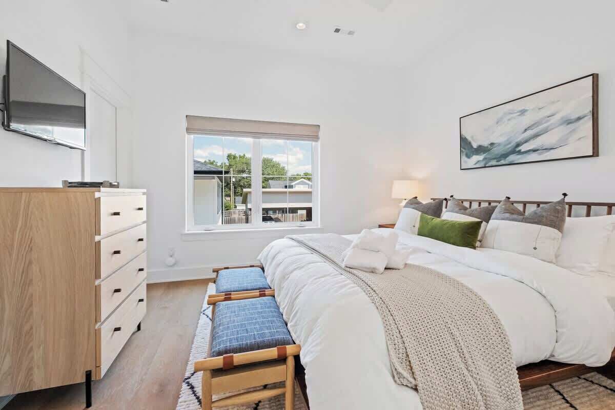 Une chambre à coucher avec un lit, un bureau, une chaise, une fenêtre et un tableau au mur.