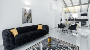 A modern living room with a black sofa, a chandelier, and a dining area with a black and white patterned rug. - Modern Apartment Black Diamond with balcony in Vrsar (Vrsar)