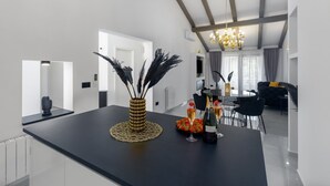 A modern kitchen with a black countertop, a decorative vase with pampas grass, and a dining area with a round table and chairs. - Modern Apartment Black Diamond with balcony in Vrsar (Vrsar)