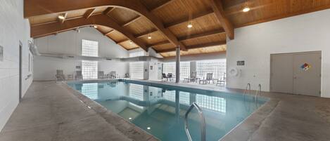 An indoor swimming pool with a wooden ceiling and clear glass walls.