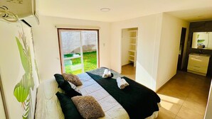 Ein Hotelzimmer mit Bett, Fenster, einer Tür zum Balkon und einer Küchenzeile.