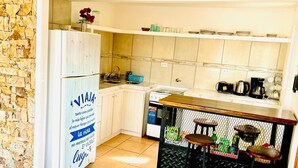 Eine kompakte Küche mit Kühlschrank, Spüle und einer Essecke mit Tisch und Stühlen.
