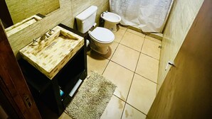 Ein Badezimmer mit Holzwaschtisch, zwei Toiletten und einer Duschvorhang.