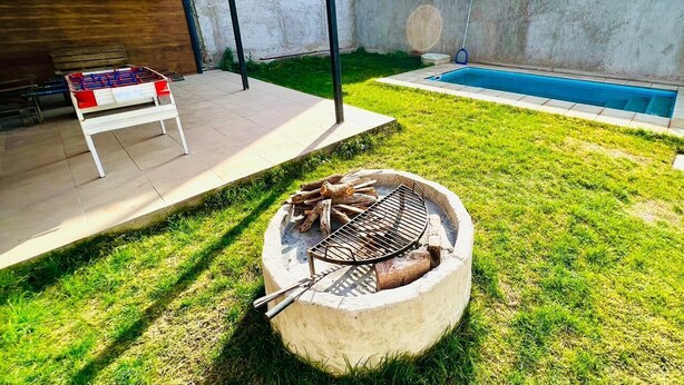 Ein Garten mit Grill, Pool und überdachter Sitzgelegenheit.