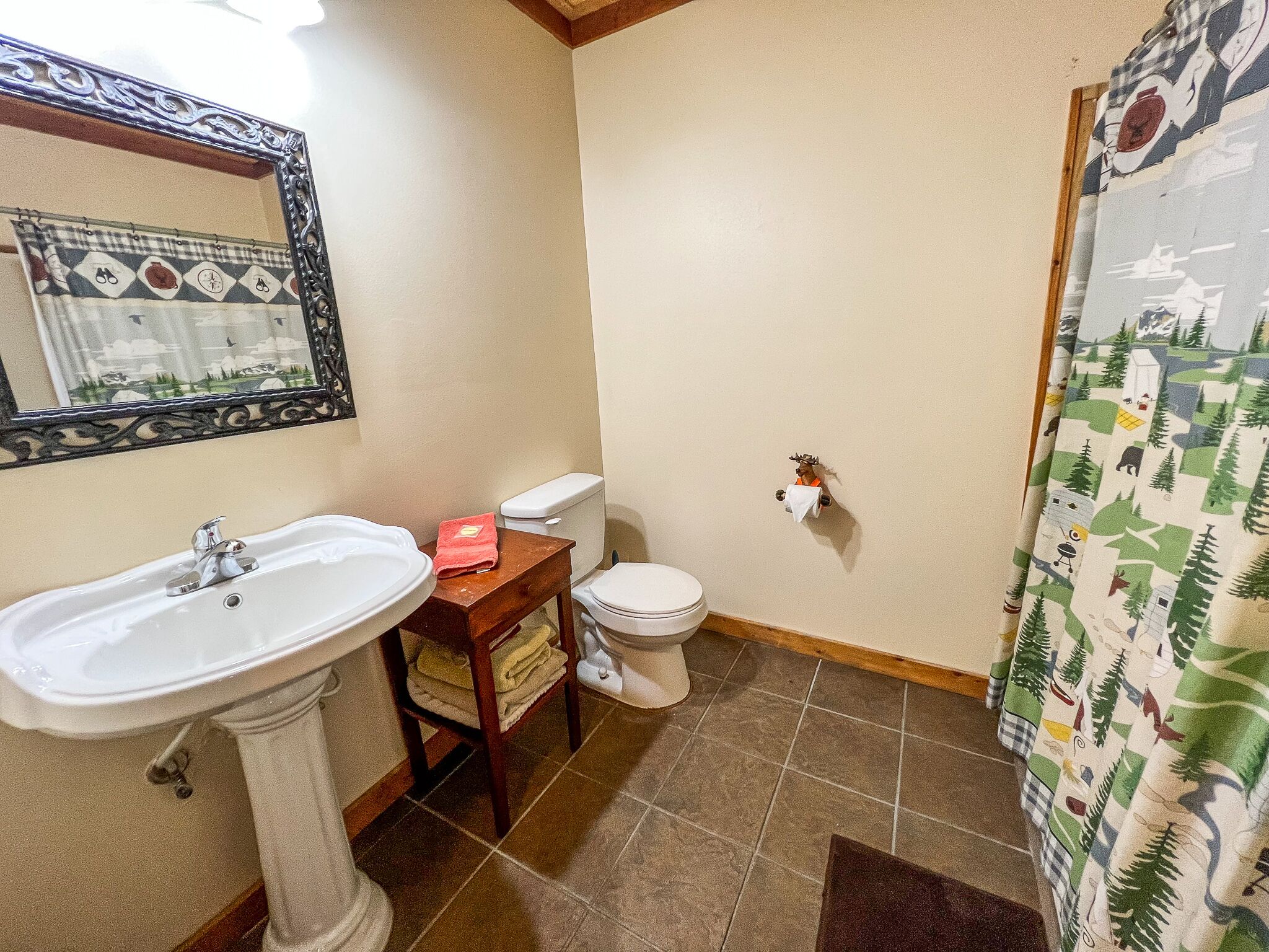 A bathroom with a white sink, toilet, and a mirror with an ornate frame.