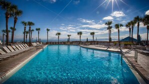 A swimming pool with lounge chairs and palm trees, surrounded by a clear sky. - Beachfront! Lg Balcony Amazing Gulf-Beach Views! (Panama City Beach)