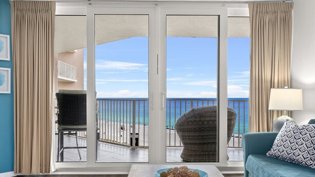 A room with a view of the beach, a sofa, a table with a bowl, and a chair. - Beachfront! Lg Balcony Amazing Gulf-Beach Views! (Panama City Beach)