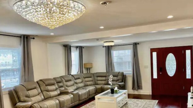 Amplio salón con un sofá de cuero en forma de L, una mesa de centro blanca y una alfombra estampada.