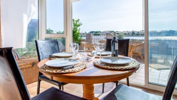 Ein Esstisch für vier Personen, mit Stühlen, Meerblick und einer verglasten Terrasse.