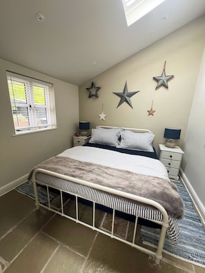 A bedroom with a bed, bedside tables, star decorations, a window, and a skylight.