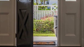 An open door leading to a garden with a white fence and greenery. - The Jasmine Gate (Casuarina)