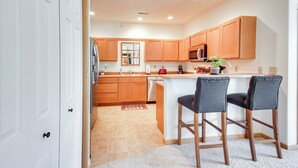 A modern kitchen with wooden cabinets, a stainless steel refrigerator, and a built-in microwave. - Cozy Livingston Condo w/ Balcony & Mtn View! (Livingston)