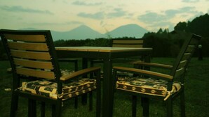 A table and four chairs with patterned cushions in an outdoor setting with a mountainous backdrop. - Da Vinci Gorilla Lodge (Muhoza)