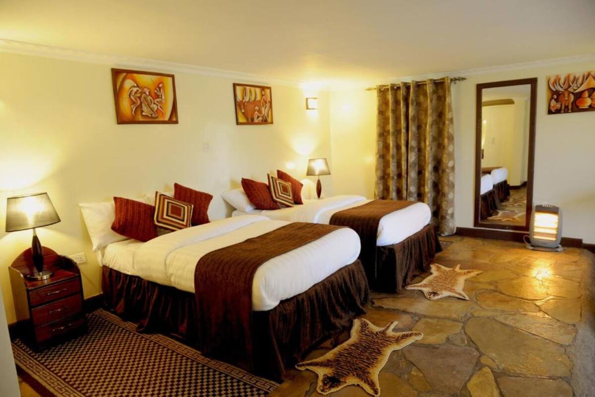 Habitación de hotel con dos camas, piso de piedra y un espejo.