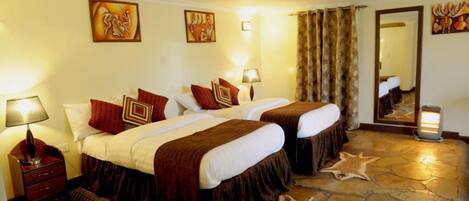 Habitación de hotel con dos camas, piso de piedra y un espejo.