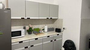 A modern kitchen with grey cabinets, a microwave, a toaster, and a trash bin. - St. Peter's Shared House (Birmingham)