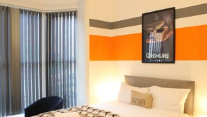 A hotel room with a bed, a chair, a window with blinds, and a poster on the wall. - St. Peter's Shared House (Birmingham)