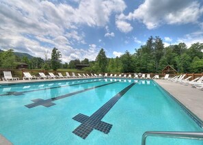 Una piscina con sillas de descanso y una valla de madera.