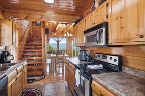 A wooden cabin kitchen with a stove, microwave, and coffee maker. - Luxurious Cabin|Majestic Views|Arcade|Hot Tub (Sevierville)