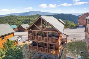 A two-story log cabin with a balcony, surrounded by a mountainous landscape. - Luxurious Cabin|Majestic Views|Arcade|Hot Tub (Sevierville)