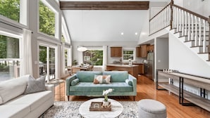 A spacious living room with a teal sofa, a coffee table, and a staircase leading to an upper level.