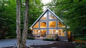 A modern house with large windows, a covered porch, and a stone pathway leading to the entrance.