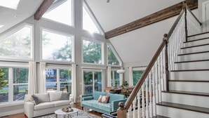 A spacious living area with large windows, a staircase, and a dining area.