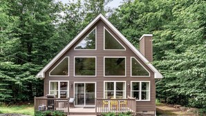 A two-story cabin with a large front porch, multiple windows, and a chimney.