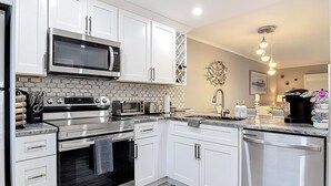 Uma cozinha moderna com armários brancos, eletrodomésticos de aço inoxidável e painel de azulejos.