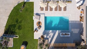 An aerial view of a resort with a swimming pool, sun loungers, umbrellas, and a wooden fence. - Mirena Luxury Living - Casa di Maria (Αφάντου)