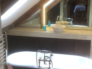 Bathroom features a bathtub, marble countertop, and large mirror.