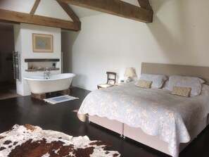 Relax in a cozy space with a large bed, wooden chair, and a bathtub.