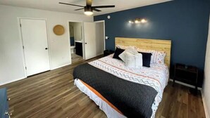 A bedroom with a wooden floor, a bed with patterned bedding, a ceiling fan, and a wall-mounted light fixture. - Wild Stallion Retreat Close to Sedona (Cottonwood)