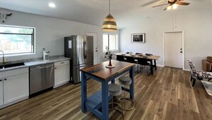 A modern kitchen with a stainless steel refrigerator, a wooden dining table with bar stools, and a ceiling fan. - Wild Stallion Retreat Close to Sedona (Cottonwood)