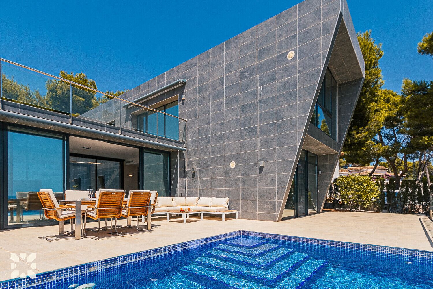 A modern house with a swimming pool, outdoor furniture, and a clear blue sky.